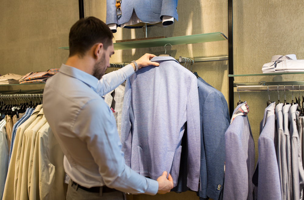 销售购物时尚风格和人们观念封闭的男人在服装店选择夹克